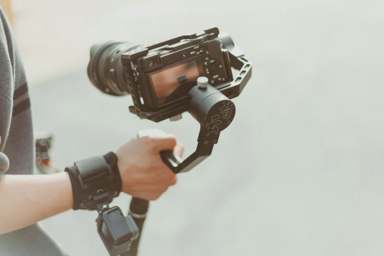 a close up of a person holding a video camera, posing for the camera