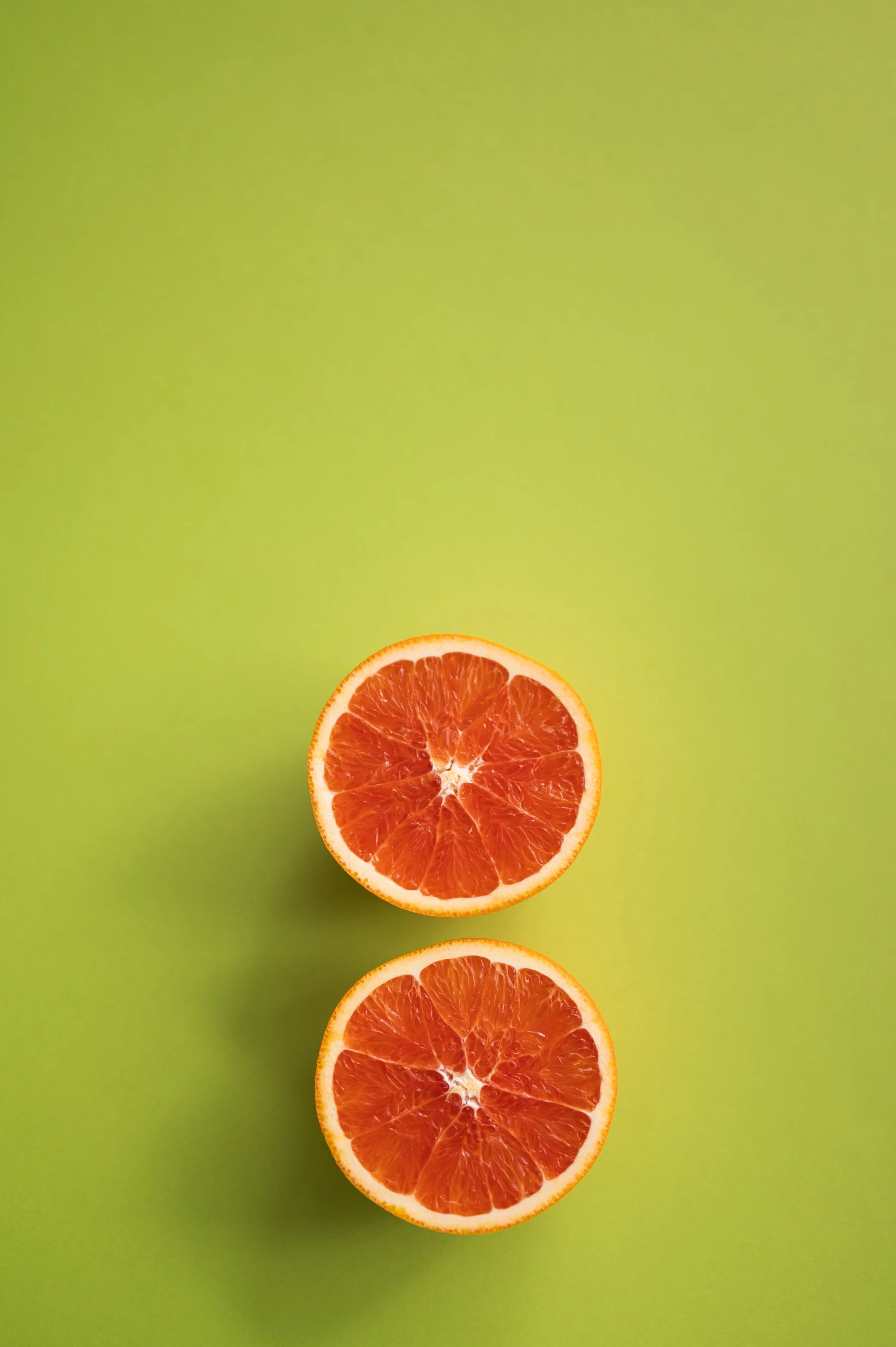 two halves of grapefruit on a green background, a picture, by Carey Morris, trending on pexels, dark orange, neighborhood, single color, raphael personnaz