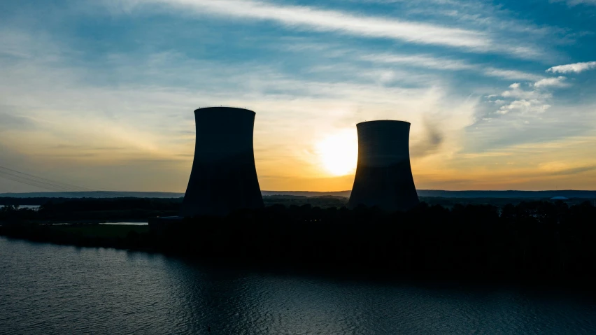 a couple of cooling towers sitting next to a body of water, pexels contest winner, nuclear art, youtube thumbnail, sundown, atom, ready to model