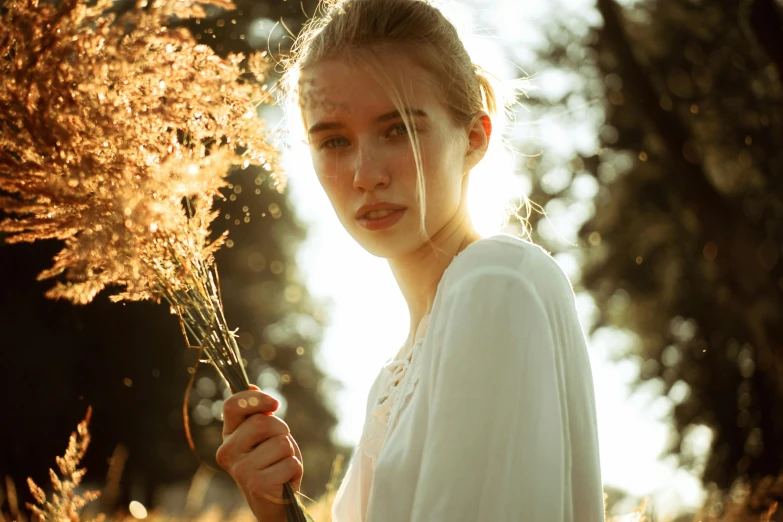 a woman holding a bunch of flowers in a field, inspired by Anka Zhuravleva, pexels contest winner, backlit face, gold dappled light, teen girl, blonde women