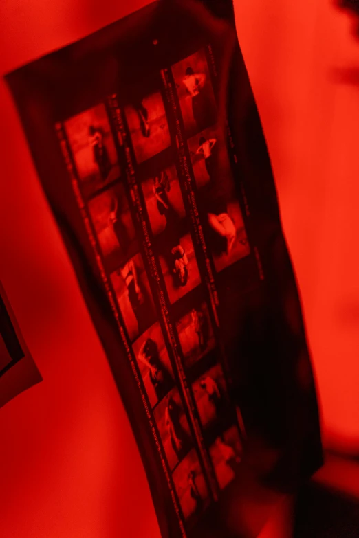 a person holding a video game controller in their hand, a silk screen, inspired by Nan Goldin, video art, atmospheric red effects, contact sheet, 33mm photo, red banners