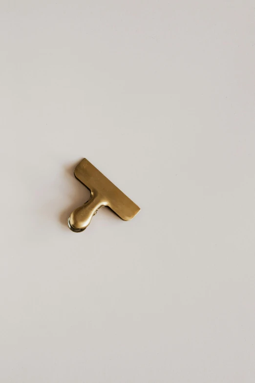 a gold letter t on a white surface, an abstract sculpture, unsplash, metal handles, 17mm, thumbnail, collection product