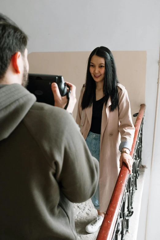 a man taking a picture of a woman on a balcony, pexels contest winner, wearing a duster coat, young asian woman, promo image, indoor picture