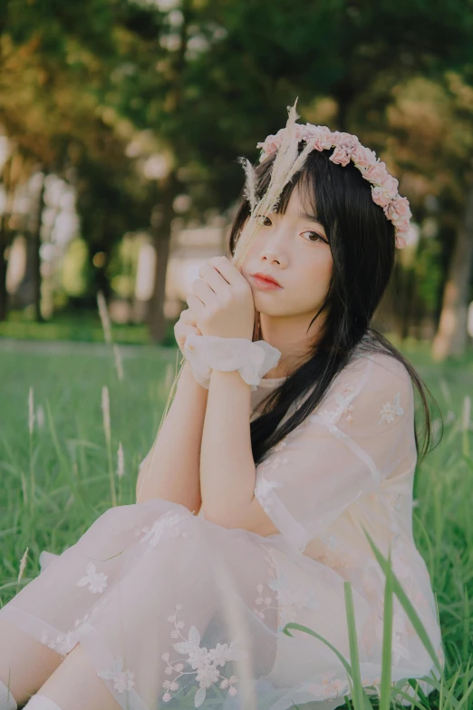 a woman sitting on top of a lush green field, an album cover, inspired by Kim Jeong-hui, unsplash, aestheticism, white flower crown, anime. soft lighting, thoughtful pose, bae suzy