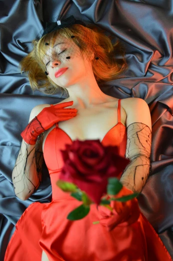 a woman laying on a bed with a rose in her hand, inspired by amano, cosplayer dressed like a crab, carole feuerman, medium close shot, asuka langley sohryu