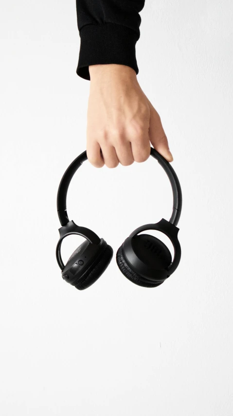 a person holding a pair of headphones in their hand, all black matte product, birdseye view, waving, thumbnail