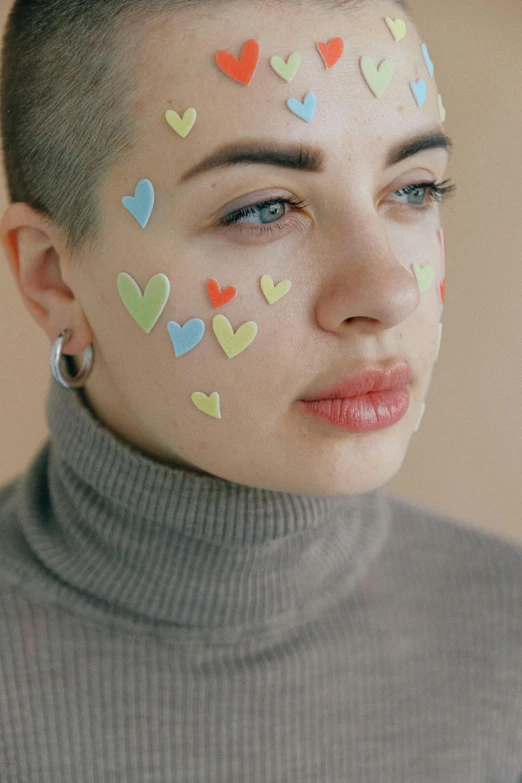 a woman with hearts painted on her face, an album cover, inspired by Elsa Bleda, trending on pexels, shaved hair, pastel art, stickers, beautiful faces aesthetic