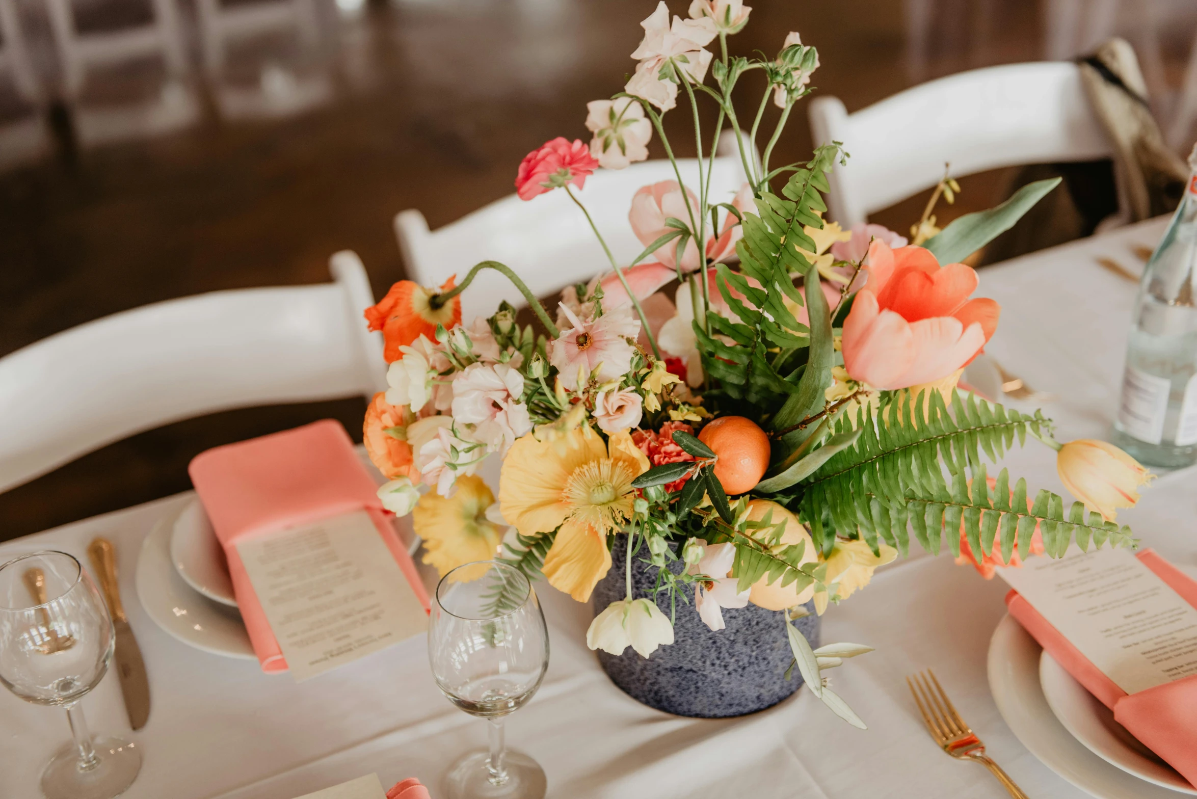 a vase filled with flowers sitting on top of a table, by Carey Morris, unsplash, group sit at table, orange pastel colors, place setting, d. i. y. venue