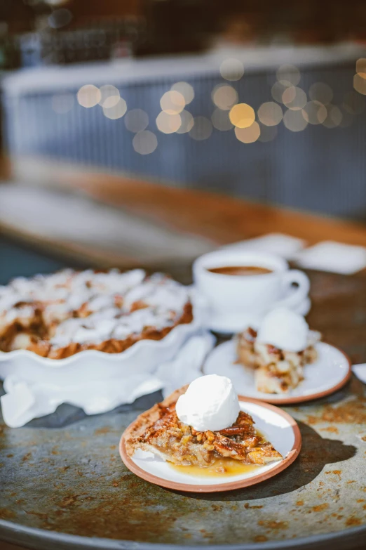 a table topped with plates of food next to a cup of coffee, by Austin English, apple pie, snow snow, bakery, lights