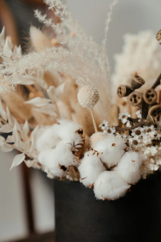 a close up of a vase of flowers on a table, lots of cotton plants, browns and whites, dried flower, zoomed in