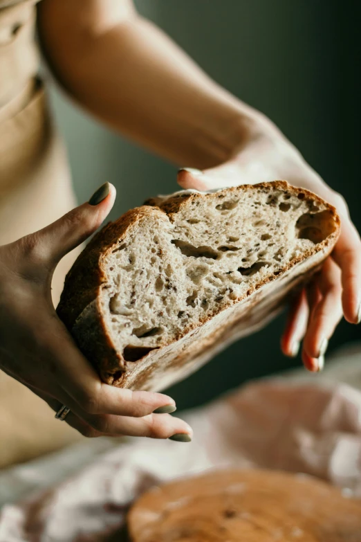 a woman holding a loaf of bread in her hands, a portrait, by Julia Pishtar, trending on pexels, back - lit, grain”