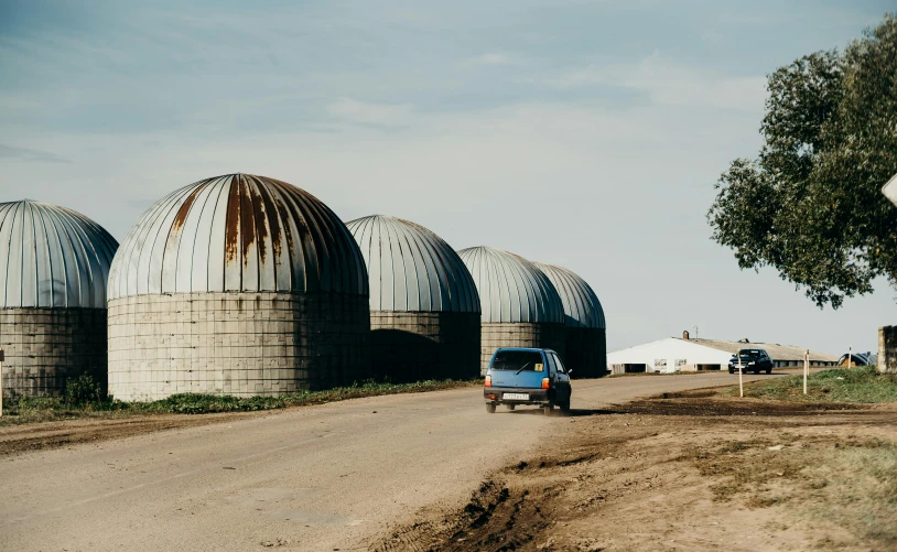 a truck driving down a dirt road next to silos, unsplash contest winner, renaissance, geodesic domes, rounded roof, soviet suburbs, propane tanks