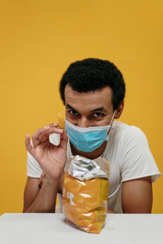 a man sitting at a table with a bag of food in front of him, a picture, surgical mask covering mouth, on yellow paper, steroid use, thumbnail