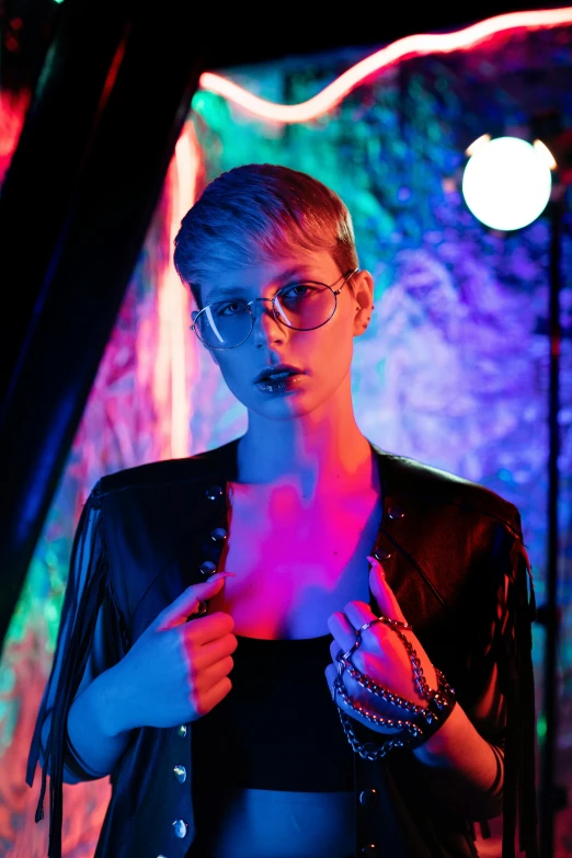 a woman standing in front of a neon light, inspired by Elsa Bleda, holography, wearing leather, androgynous male, wearing black rimmed glasses, modeling photography