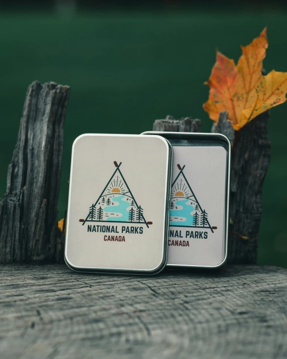 a couple of tins sitting on top of a wooden table, full card design, camp, official product photo, dark. no text