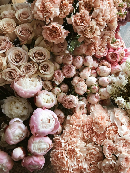 a bunch of flowers sitting on top of a table, in shades of peach, various sizes, soft and intricate, voluminous