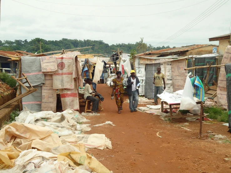 a group of people walking down a dirt road, small buildings, ldpe, artisanal art, biroremediation