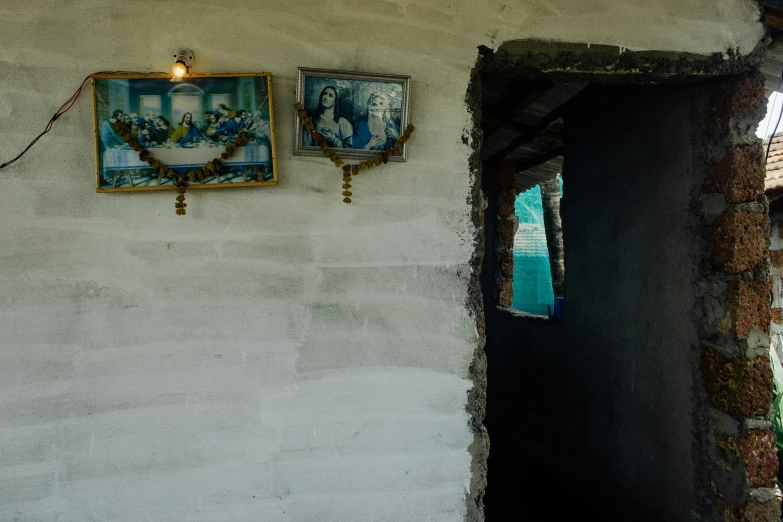 a couple of pictures hanging on the side of a wall, by Lucia Peka, inside house in village, inside a tomb, taken with sony alpha 9, religious