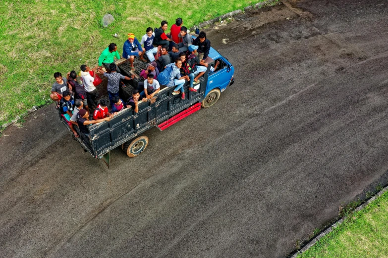a group of people riding in the back of a truck, by Basuki Abdullah, pexels contest winner, city of armenia quindio, high - angle, square, mx2