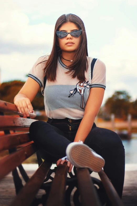 a woman sitting on top of a wooden bench, a colorized photo, trending on pexels, cute casual streetwear, wearing polo shirt, with sunglass, adriana chechik