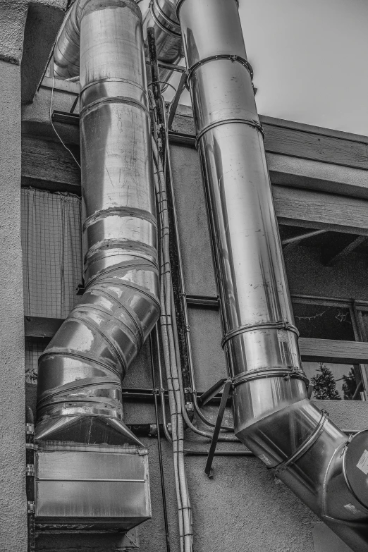 a tall metal pipe sticking out of the side of a building, a black and white photo, by Sven Erixson, unsplash, smoking vessels, made out of shiny silver, machinery, colours