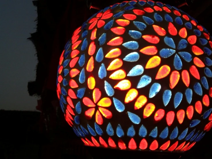 a colorful lamp hanging from the side of a building, a mosaic, pixabay, glowing magma sphere, carved from sapphire stone, gardening, low saturated red and blue light