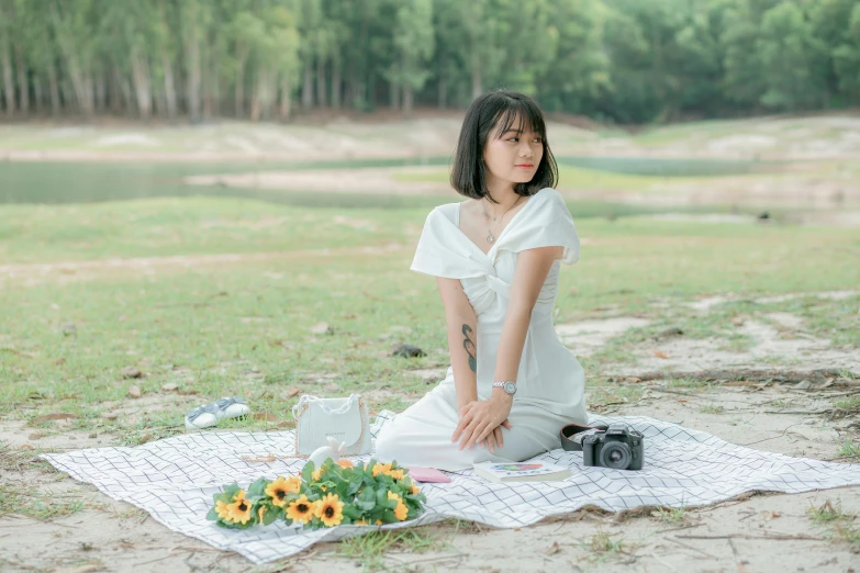 a woman sitting on a blanket in a field, inspired by Kim Du-ryang, pexels contest winner, on a white table, dressed in white, patiphan sottiwilai, picnic