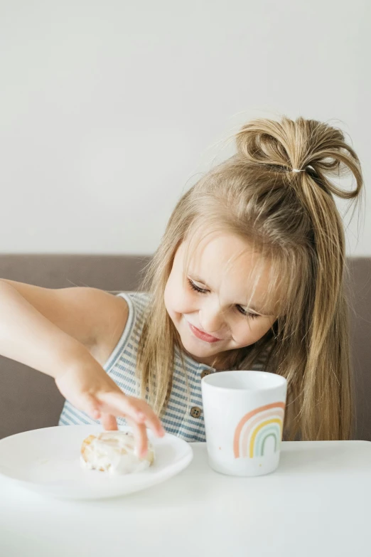 a little girl sitting at a table with a plate of food, pastel faded grey rainbow, with a white mug, product shot, topknot