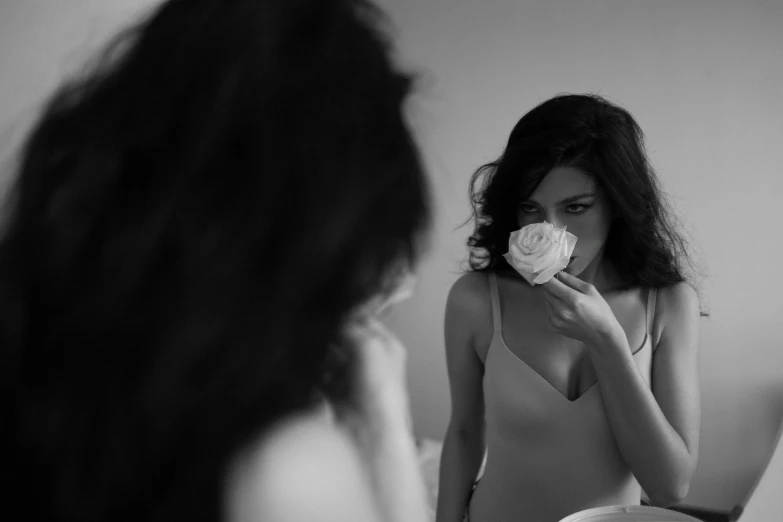 a woman standing in front of a mirror holding a flower, a black and white photo, by Sergio Burzi, unsplash, romanticism, kendall jenner, 4k movie still, selena gomez, porcelain
