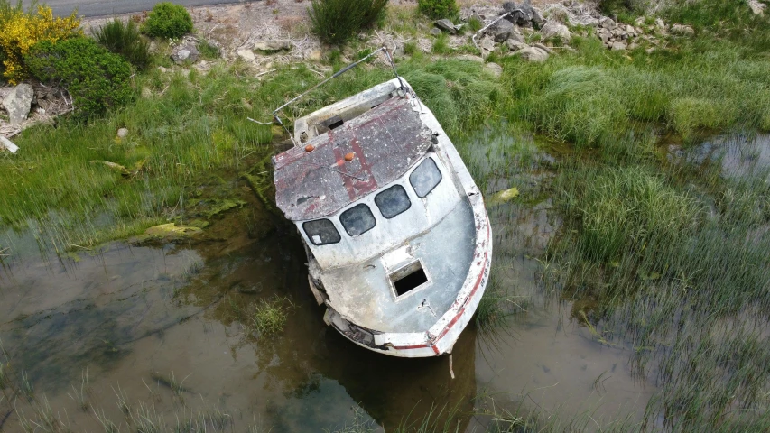 a boat that is sitting in some water, derelict, photograph from above, creek, confident looking