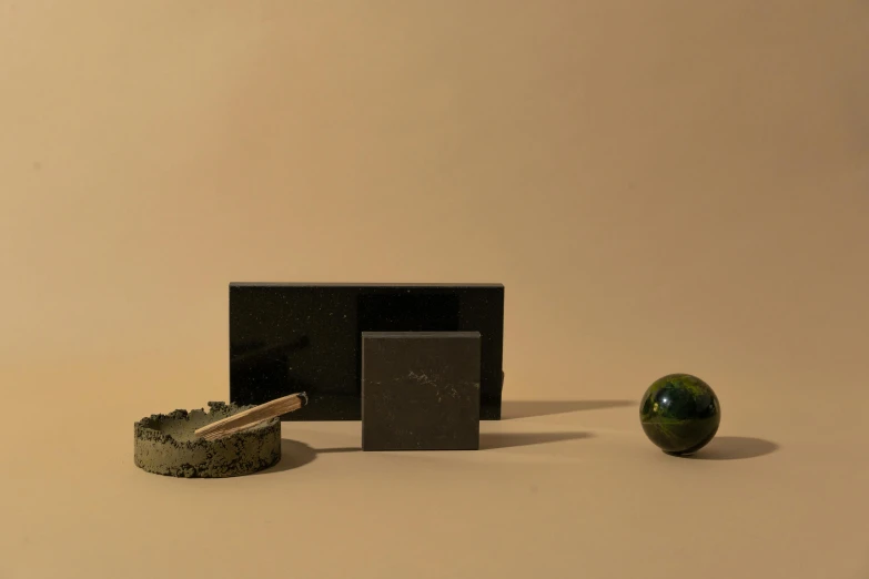 a black box sitting on top of a table next to a green apple, a still life, by Emma Andijewska, assemblage, marble reflexes, various sizes, dwell, meteorite