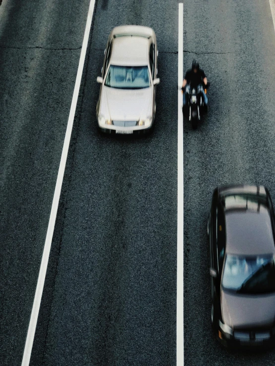 a couple of cars driving down a street next to a motorcycle, pexels contest winner, renaissance, topdown, lost highway, low quality photo, full frame image