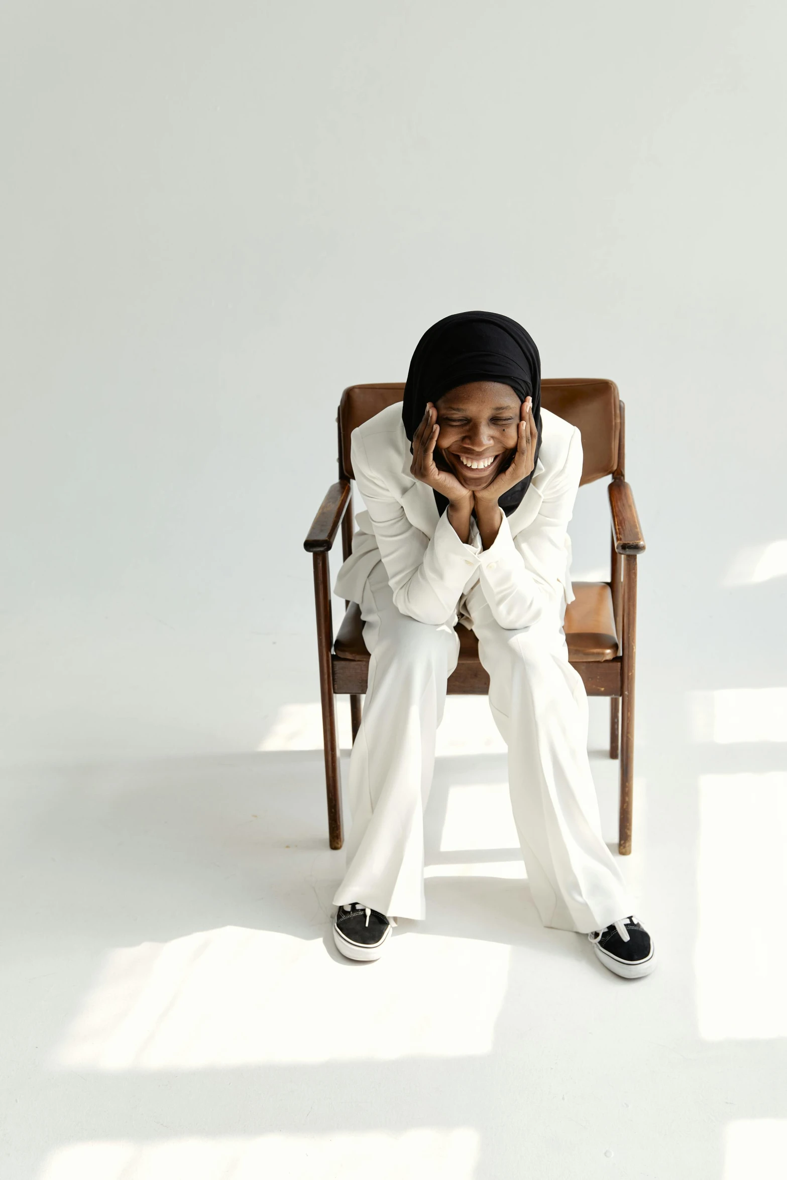 a person that is sitting in a chair, inspired by Ella Guru, hurufiyya, all white, head bent back in laughter, muslim, androgynous person