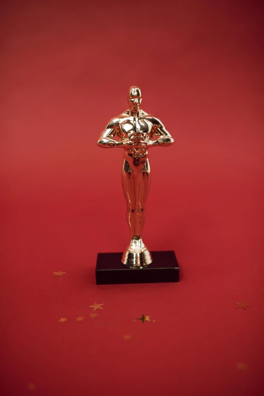 a statue of a man standing on a red surface, pexels contest winner, photorealism, winner of seven oscars, vhs, gold body, 1990s photograph