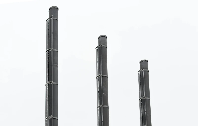 a group of metal pipes sitting next to each other, by Jørgen Nash, three towers, minimalist photo, black plastic, smokestacks