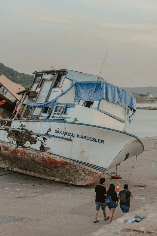 a boat sitting on top of a sandy beach, inspired by Tsuchida Bakusen, happening, scrapyard architecture, jakarta, front top side view, high damage