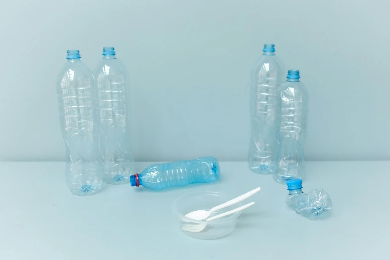 three empty plastic bottles and a spoon on a table, by Maeda Masao, plasticien, 6 pack, light-blue, large, various items