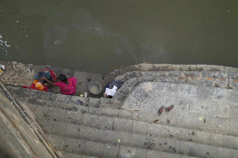 a group of people standing next to a body of water, a picture, sewers, sitting on temple stairs, birdseye view, thumbnail