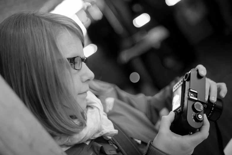 a black and white photo of a woman holding a camera, flickr, happening, kirsi salonen, looking distracted, low dof, taken in the late 2010s
