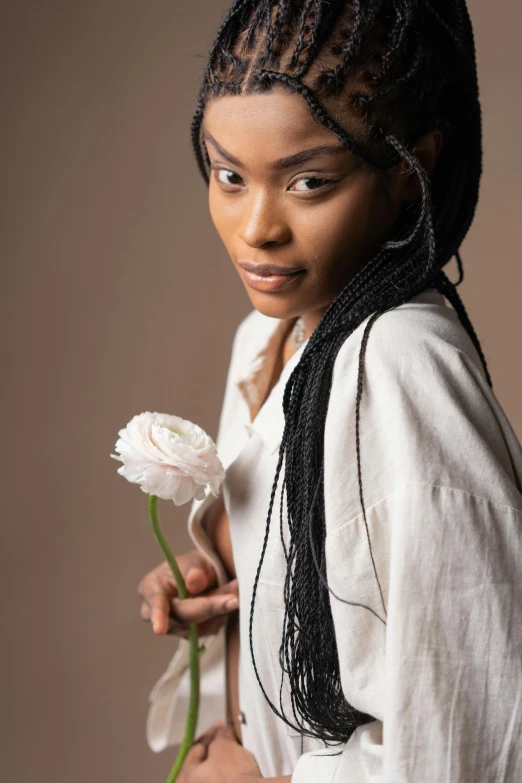 a woman in a white shirt holding a flower, inspired by Theo Constanté, trending on pexels, renaissance, black teenage girl, studio photoshoot, datura, loose white braid