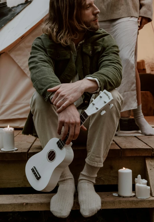 a man that is sitting down with a guitar, trending on pexels, romanticism, holding a candle holder, glamping, wearing white clothes, profile image