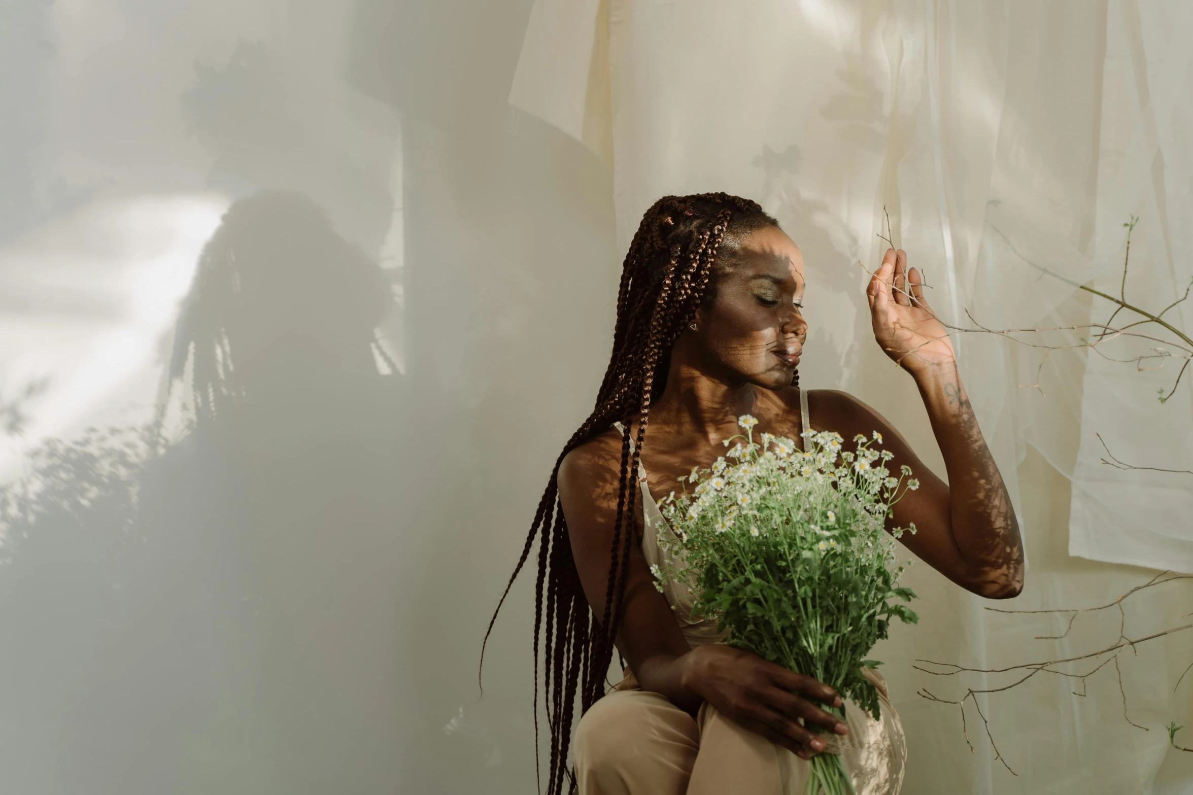 a woman holding a bunch of white flowers, pexels contest winner, visual art, box braids, in white room, queer woman, in a sunbeam