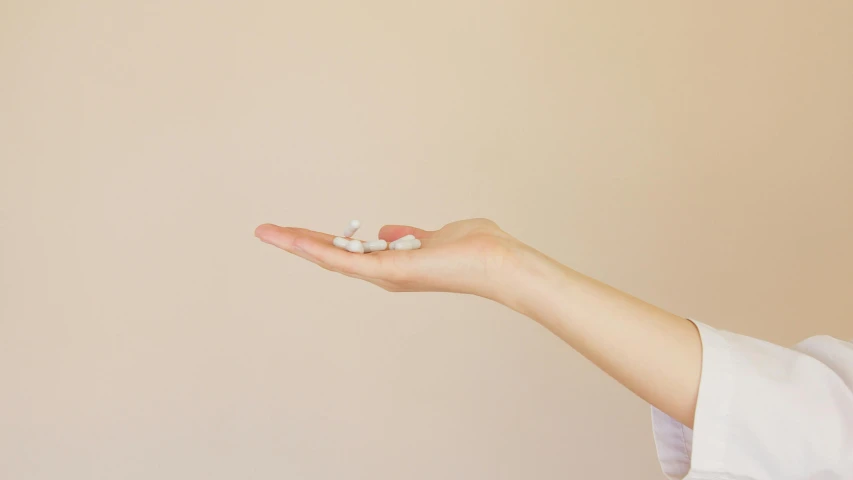 a woman holding a pill in her hand, by Évariste Vital Luminais, unsplash, antipodeans, white clay, 3/4 side view, palm body, marshmallow