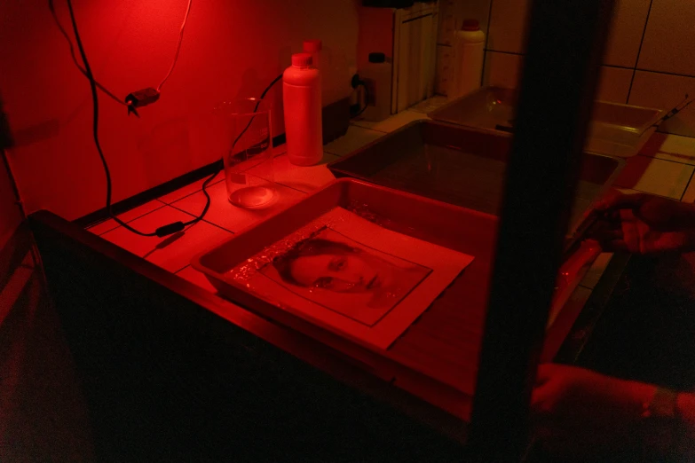 a sink under a red light in a bathroom, a silk screen, face and skin is dark red, for printing, aperture science test chamber, ignant