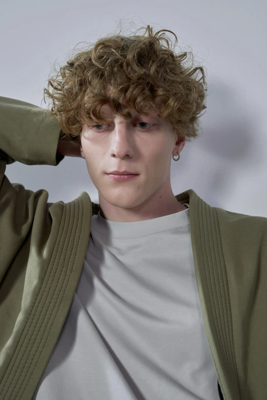 a man with curly hair posing for a picture, an album cover, inspired by Willem Labeij, loosely cropped, at a fashion shoot, round-cropped, muted green