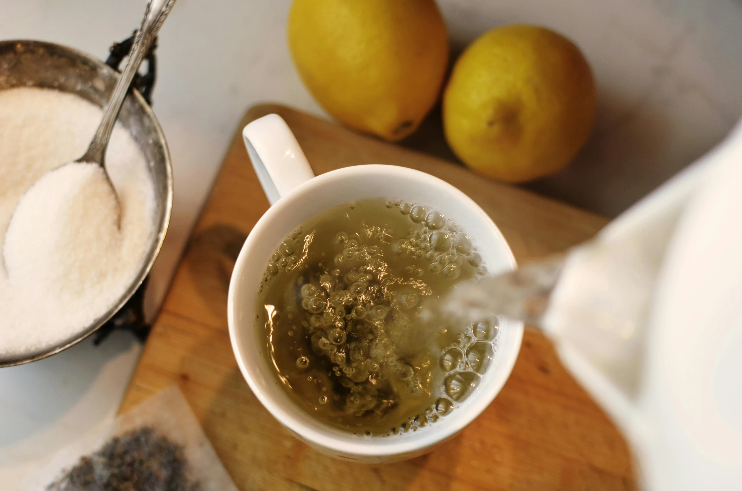 a cup of tea and some lemons on a table, pexels, renaissance, green steam rising from soup, dried herbs, “wide shot, pouring