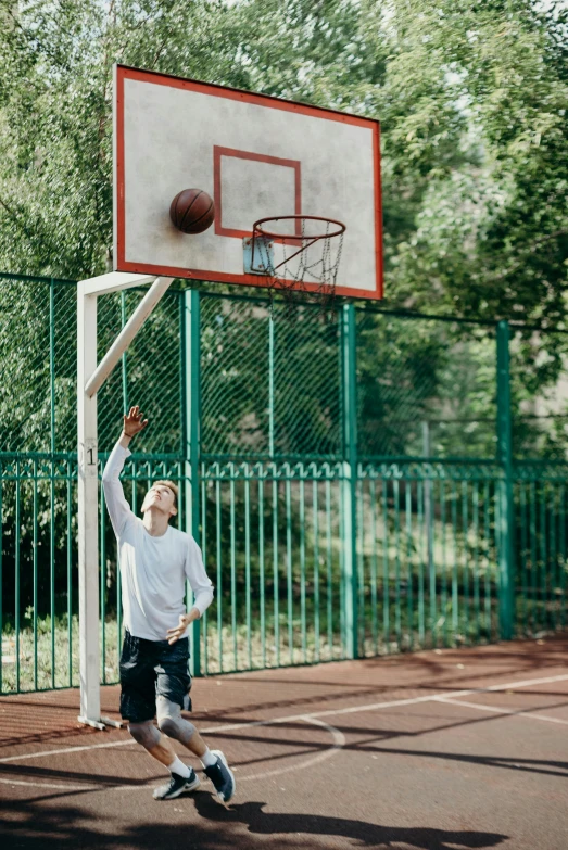 a man standing on top of a basketball court holding a basketball, by Paul Bird, trending on dribble, daniil kudriavtsev, at a park, dunking, aged 13