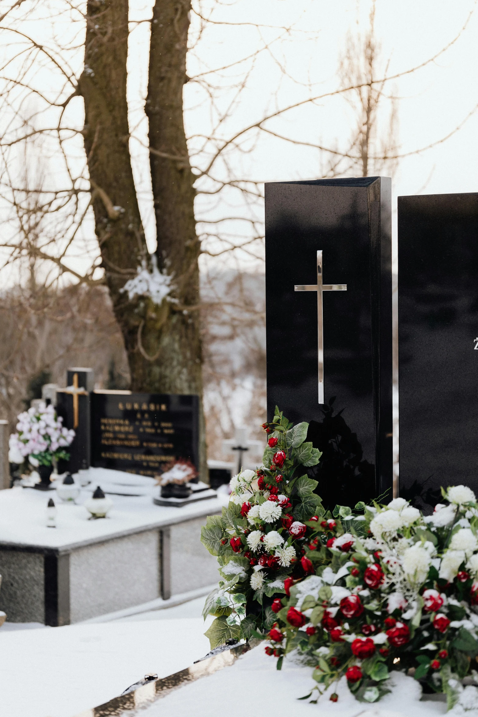 a couple of tombstones sitting next to each other in the snow, a photo, unsplash, vanitas, a man wearing a black jacket, presidential cross, flower decorations, lights on