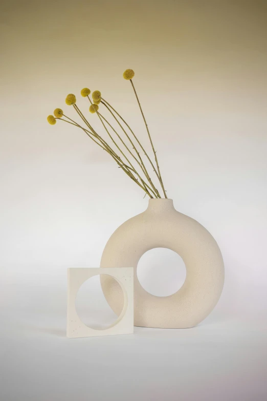 a white vase with some yellow flowers in it, an abstract sculpture, inspired by Isamu Noguchi, new sculpture, round windows, modern minimalist f 2 0, square, soft white rubber