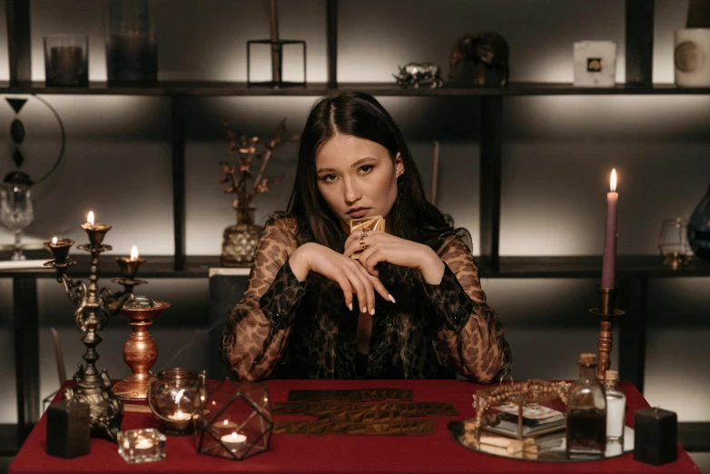 a woman sitting at a table with candles, an album cover, gemstones and gold, dilraba dilmurat, as a tarot card, brown